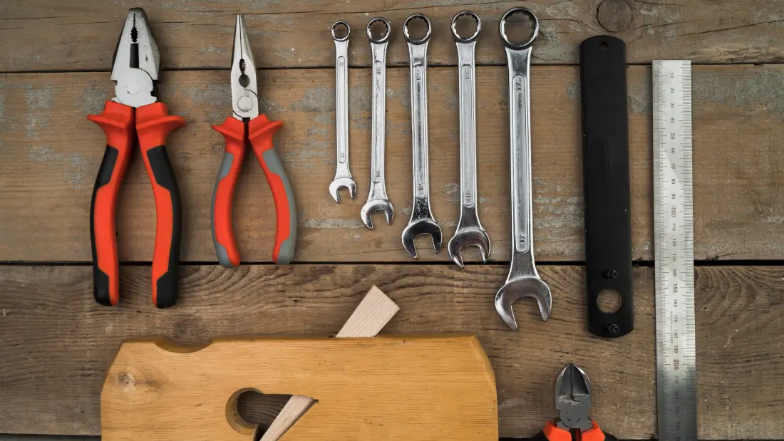 An assortment of DIY tools carefully placed on a wooden work surface.