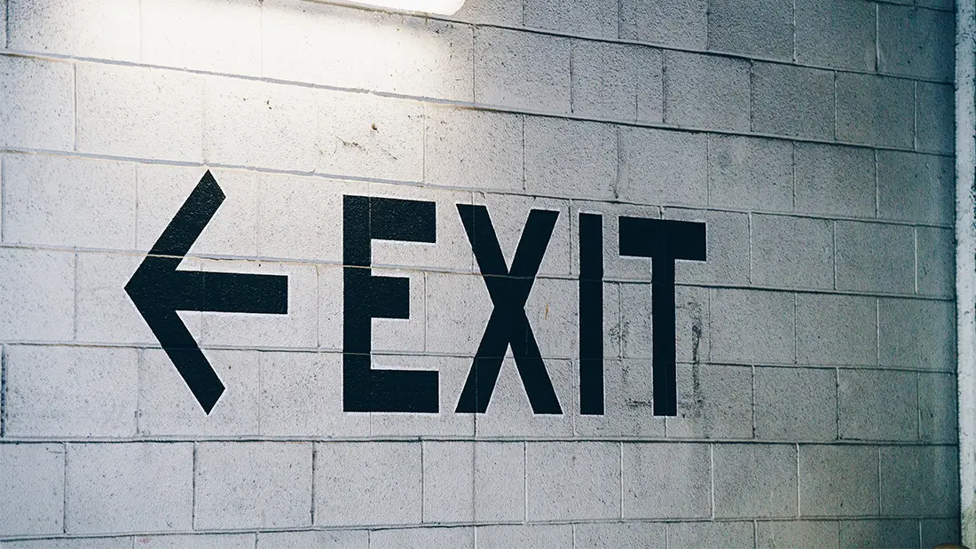 Black exit sign with arrow on a cinder block wall